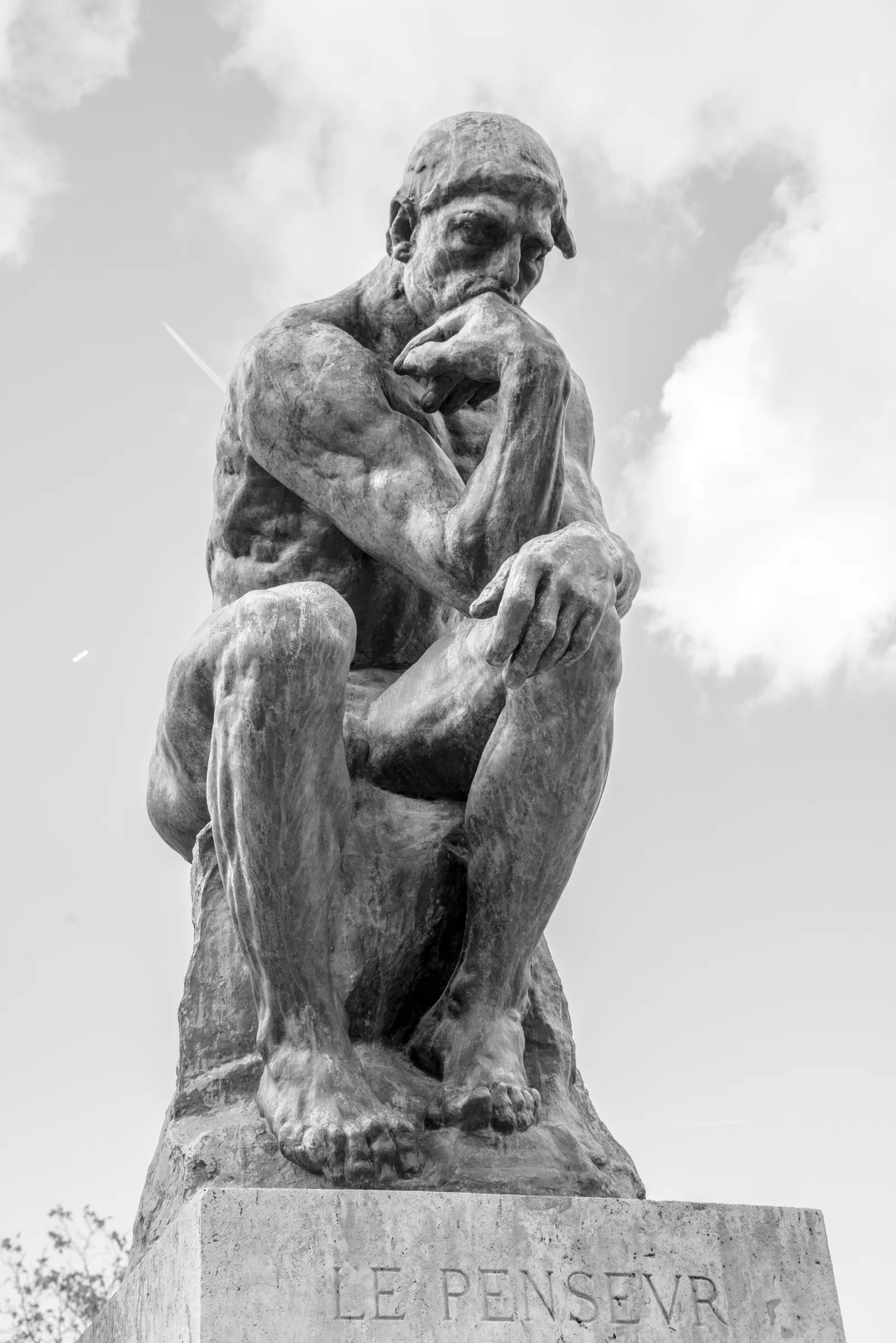 Auguste Rodin’s The Thinker sculpture against a cloudy sky